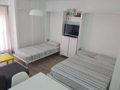 mały pokój z dwoma łóżkami i telewizorem w obiekcie New apartamento Jupiter w mieście Benalmádena