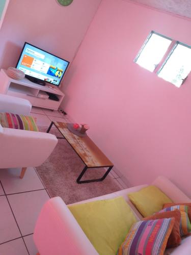 ein Wohnzimmer mit einem TV und einem Sofa in der Unterkunft Villa k'nel in Rivière-Pilote