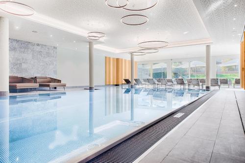 a swimming pool with chairs in a building at Obermühle 4*S Boutique Resort in Garmisch-Partenkirchen