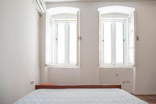 sypialnia z białymi ścianami i dwoma oknami w obiekcie Apartment Old Town w mieście Herceg Novi