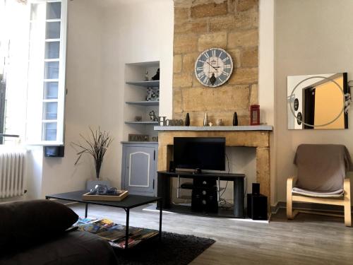 - un salon avec une cheminée et une horloge murale dans l'établissement L'instant Sarladais, à Sarlat-la-Canéda