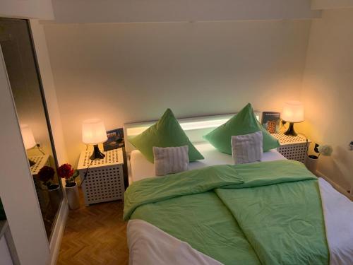 a bedroom with a bed with green sheets and pillows at Schick Hamburg in Geesthacht