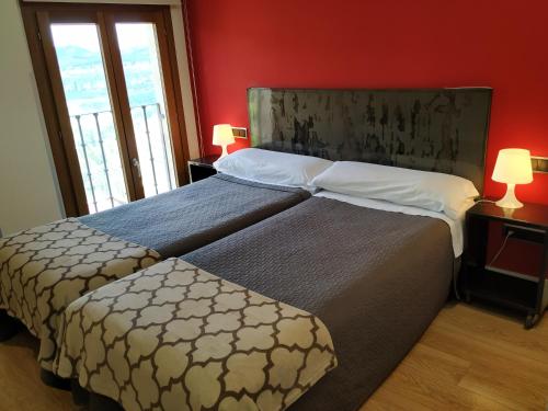 1 dormitorio con 2 camas y pared roja en Alizaque Lodge, en Cuenca