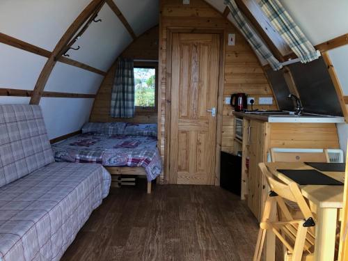a bedroom with a bed and a kitchen in a cabin at Loch Shin Glamping Pods in Lairg