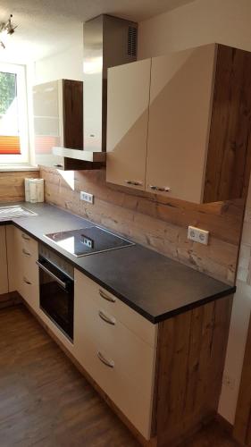 a kitchen with white cabinets and a black counter top at 4 Jahreszeiten in Tamsweg