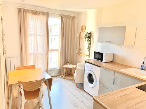 une cuisine avec une table et une machine à laver dans l'établissement JADE Appartement, à Manosque