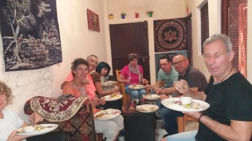 a group of people sitting in a room with plates of food at Mother Hostel in Varanasi