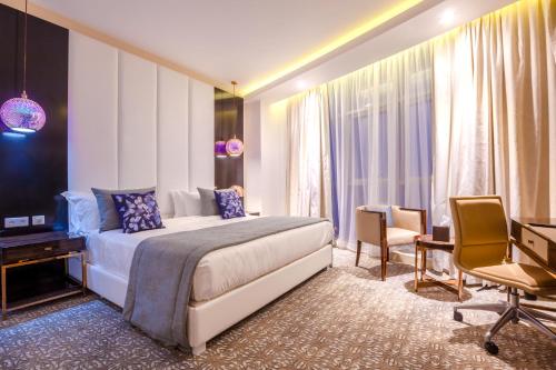 ein Hotelzimmer mit einem Bett, einem Schreibtisch und Stühlen in der Unterkunft Ferdi Lilly in Ben ʼAknoûn