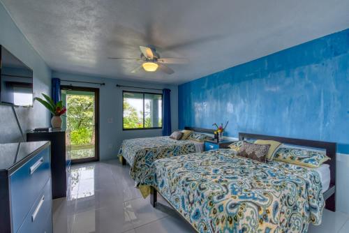 two beds in a room with blue walls at Hotel Casa Conley Del Mar in Puerto Viejo