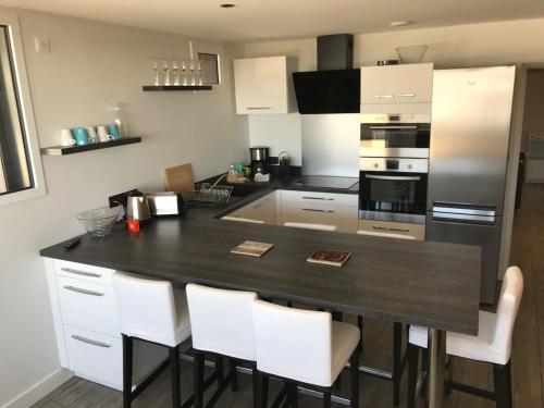 une cuisine avec un comptoir noir et des chaises blanches dans l'établissement Appartement au pied des pistes, à Besse-et-Saint-Anastaise