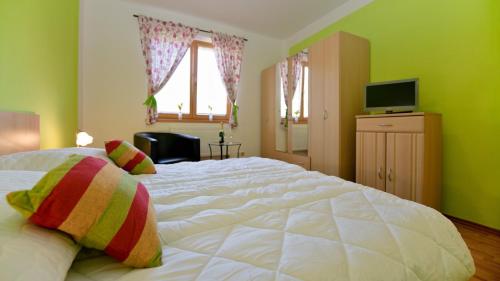a bedroom with a large white bed and a television at Wellness Penzion Eva in Dolní Moravice