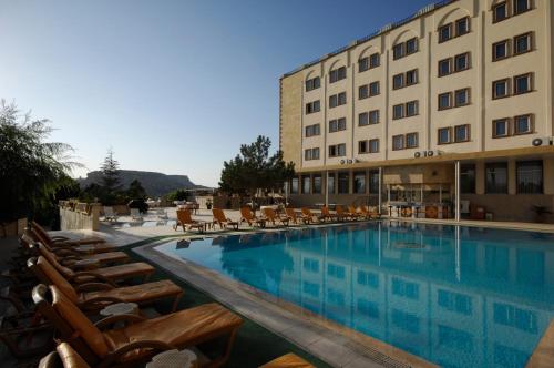 un hotel con piscina con sillas y un edificio en Dinler Hotels Urgup, en Ürgüp