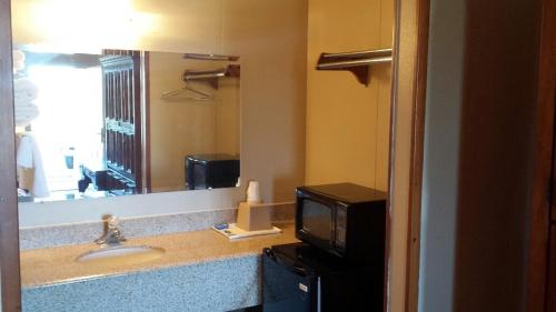 a bathroom with a sink and a mirror and a television at Carefree Inn Flatonia in Flatonia
