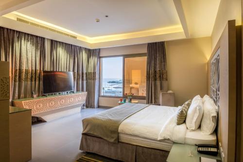 a bedroom with a large bed and a large window at Ewaa Express Hotel - Al Hamra in Jeddah