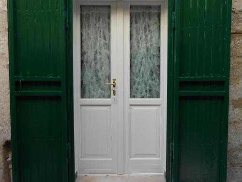 a white door with green shutters on a building at Matera's B&B in Matera