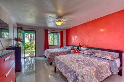 two beds in a room with red walls at Hotel Casa Conley Del Mar in Puerto Viejo