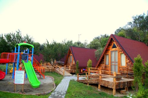 a playground in front of a log cabin at Kazdaglari Ida Natura Bungalov Hotel in Akçay