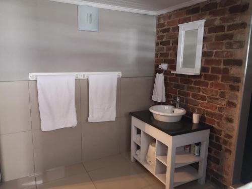 a bathroom with a sink and a brick wall at Arend Cottage in Nelspruit