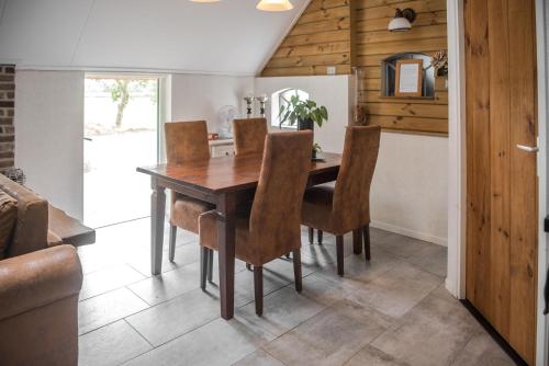 a dining room with a wooden table and chairs at Appartement de Berghoeve in Ruinen