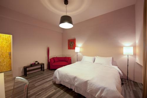 a bedroom with a white bed and a red chair at Leo 111/Arena Ruifeng in Kaohsiung