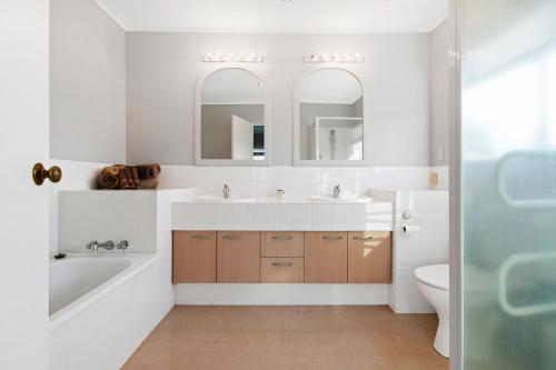 a bathroom with two sinks and a tub and a toilet at Maxwell's Golf Retreat in Bombay