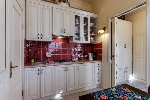 una cocina con armarios blancos y azulejos rojos en Studios at Anchevskih 3 en Leópolis