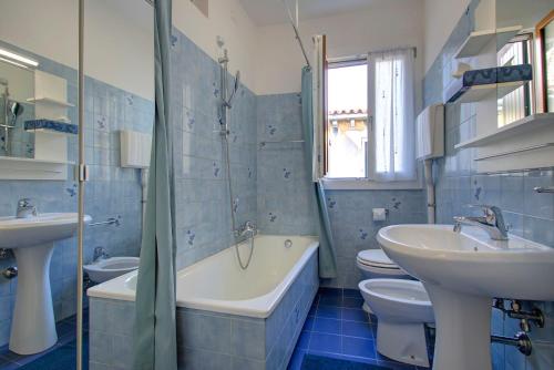 - une salle de bains carrelée de bleu avec deux lavabos, une baignoire et des toilettes dans l'établissement RECIOTO Rialto-Market, à Venise