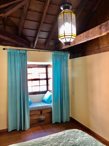 a bedroom with a window with blue curtains at Hotel Rural Vilaflor Self check in 24h in Vilaflor