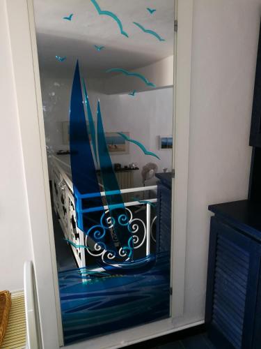 a room with a glass door with a painting of a sailboat at Celle mare con posto auto coperto in Celle Ligure