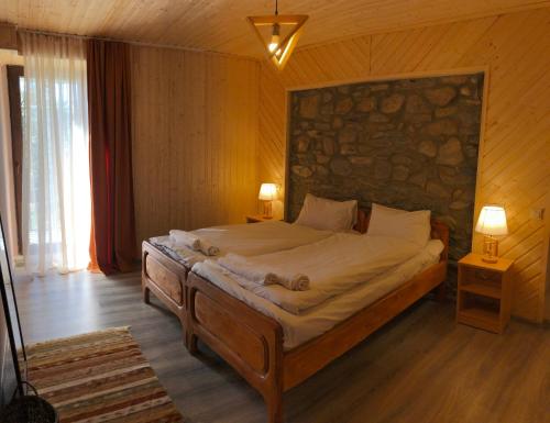 una camera da letto con un grande letto e un muro in pietra di Guest House Keti Margiani Mestia a Mestia