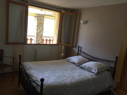 a bedroom with a bed with two pillows and a window at La soulane in Ax-les-Thermes