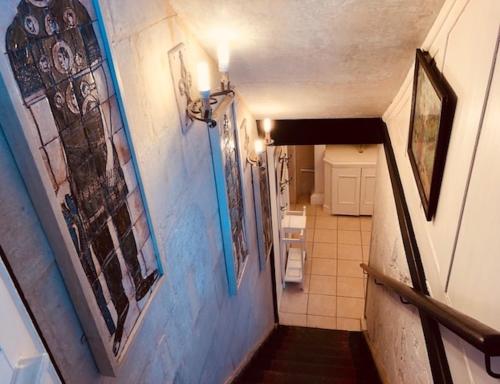 a hallway with blue walls and a stairway with paintings at Lauras Townhouse Apartments Grand Garden Apartment in Bath
