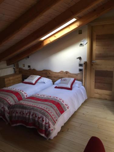 Un dormitorio con dos camas con mantas rojas y blancas. en LTHorses & Dreams, en La Thuile