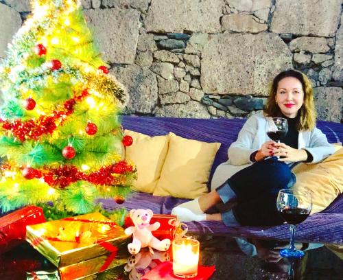 a woman sitting on a couch next to a christmas tree at Hotel Rural Vilaflor in Vilaflor