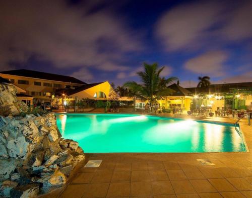Alisa Hotel North Ridge في آكرا: حمام سباحة كبير في الليل مع أضواء