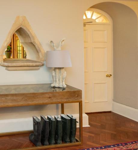 a row of black boots on a table with a lamp at Lords Of The Manor in Upper Slaughter