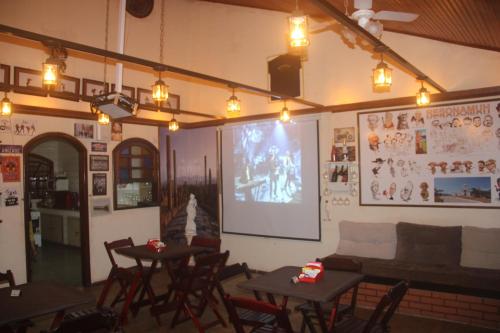 een restaurant met tafels en stoelen en een groot scherm bij RESONAMUH - Hostel in São Pedro da Aldeia