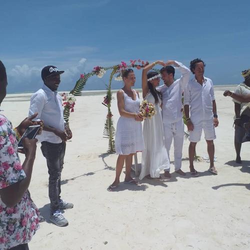 a bride and groom and their wedding party on the beach at BeB Sardegna2 Anjumasa village in Watamu