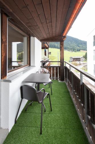 a balcony with green flooring and a table and chairs at Agrimonia - möbilierte Ferienwohnung mit Balkon in Davos