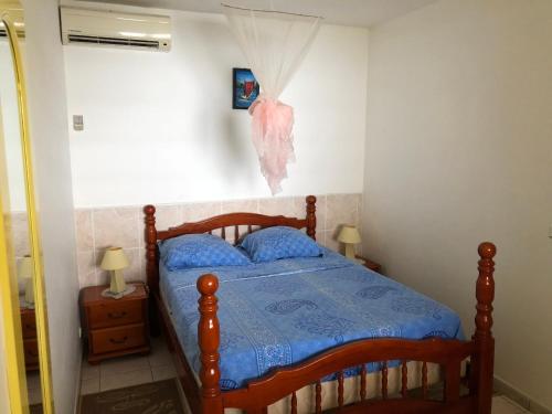 a bedroom with a wooden bed with a blue comforter at À LA VUE DE l'ANSE - T2 - LES ANSES-D'ARLET - PETITE ANSE in Quartier du Fond Fleuri