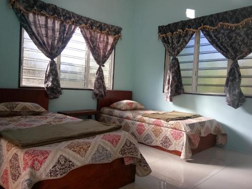two beds in a room with two windows at RoomStay Tok Abah A in Kuala Rompin