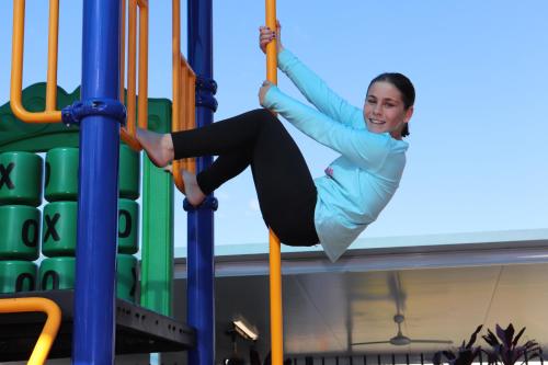 a woman is swinging on a playground at Nobby Beach Holiday Village in Gold Coast