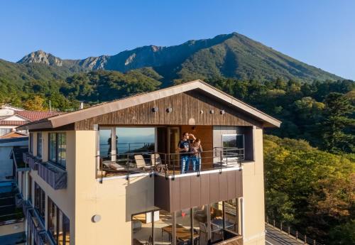 a couple standing on the balcony of a house with mountains in the background at ITADAKI Daisen 大山参道ホテル頂 in Daisen