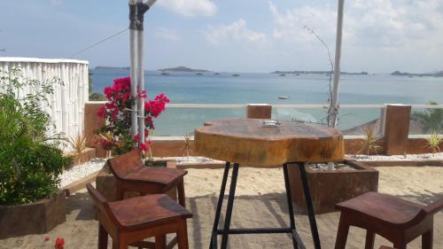 a table and chairs with a view of the ocean at Silver Fern Beach Retreat in Sekotong