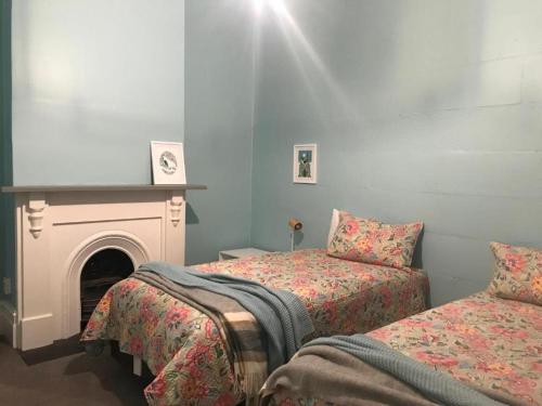 a bedroom with two beds and a fireplace at Orla's Cottage in Oamaru