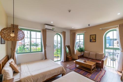 a living room with a bed and a couch and windows at NẮNG House in Da Nang