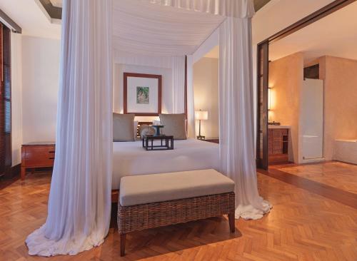 a bedroom with a white canopy bed with a ottoman at The Legian Seminyak, Bali in Seminyak