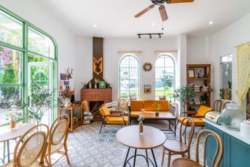 a living room with tables and chairs and windows at NẮNG House in Da Nang