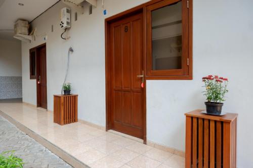 a hallway with a wooden door and two potted plants at RedDoorz near Alun Alun Kudus 2 in Kudus