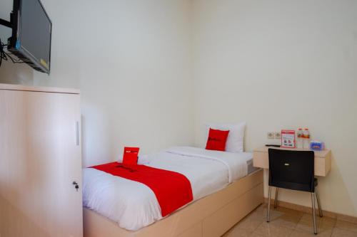 a small bedroom with a bed and a television at RedDoorz near Alun Alun Kudus 2 in Kudus